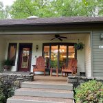 A photo of a charming porch at the Fabulous Family Lakehouse in Heber Springs, Arkansas. The porch is furnished with rocking chairs, and a table.