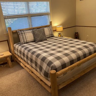 Image of a queen-size bed in a bedroom at the Fabulous Family Lakehouse in Heber Springs, Arkansas. The bed includes a fluffy comforter and high thread count linens.
